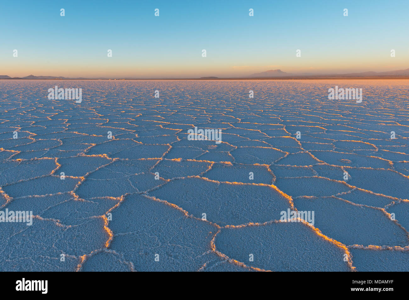 Tramonto nelle sale di Uyuni piatto (Salar de Uyuni) con gli ultimi raggi di sole che splende su il minerale formazioni esagonali, Bolivia, Sud America. Foto Stock