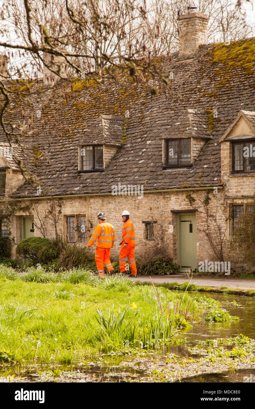 Operai in arancione hi vis usura di lavoro al di fuori di Arlington fila in English Cotswold village di Bibury Gloucestershire proprietà del National Trust in Inghilterra Foto Stock