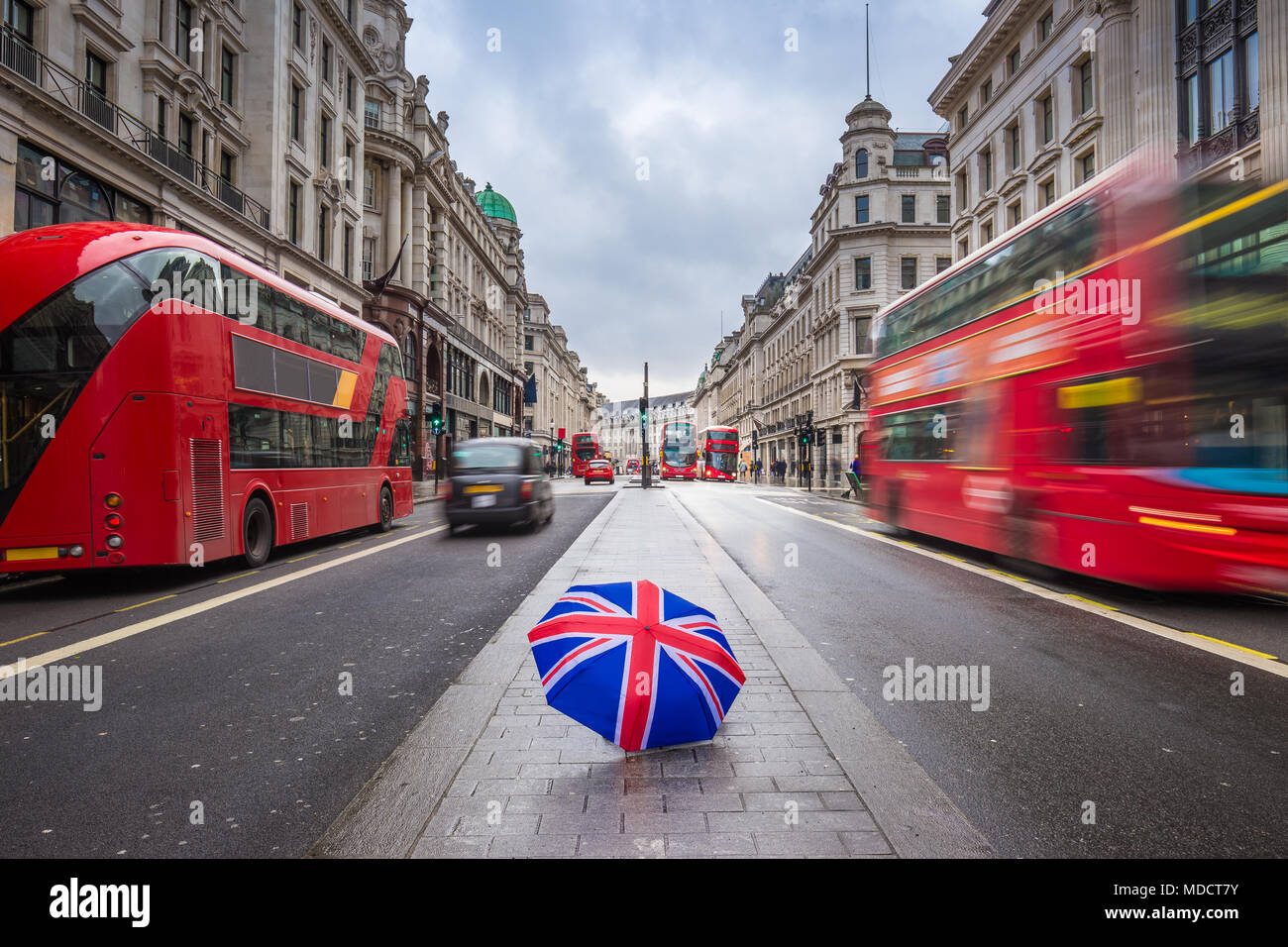 Londra, Inghilterra - British ombrello occupato a Regent Street con iconica red double-decker bus e taxi neri in movimento Foto Stock
