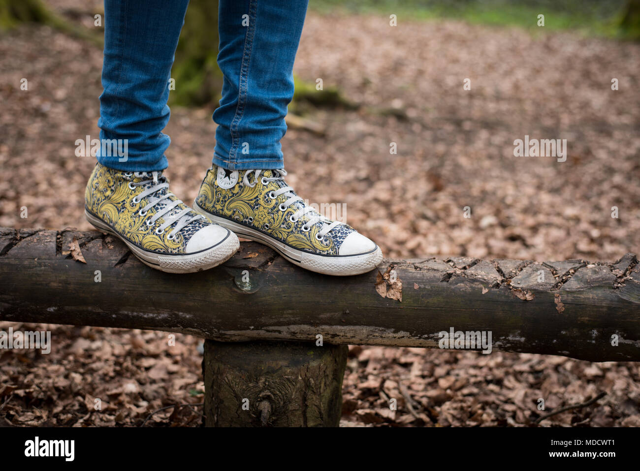 Vista della ragazza in piedi in giallo converse dei formatori come ella  saldi su un log in un parco giochi per bambini a Dunstable Downs Foto stock  - Alamy