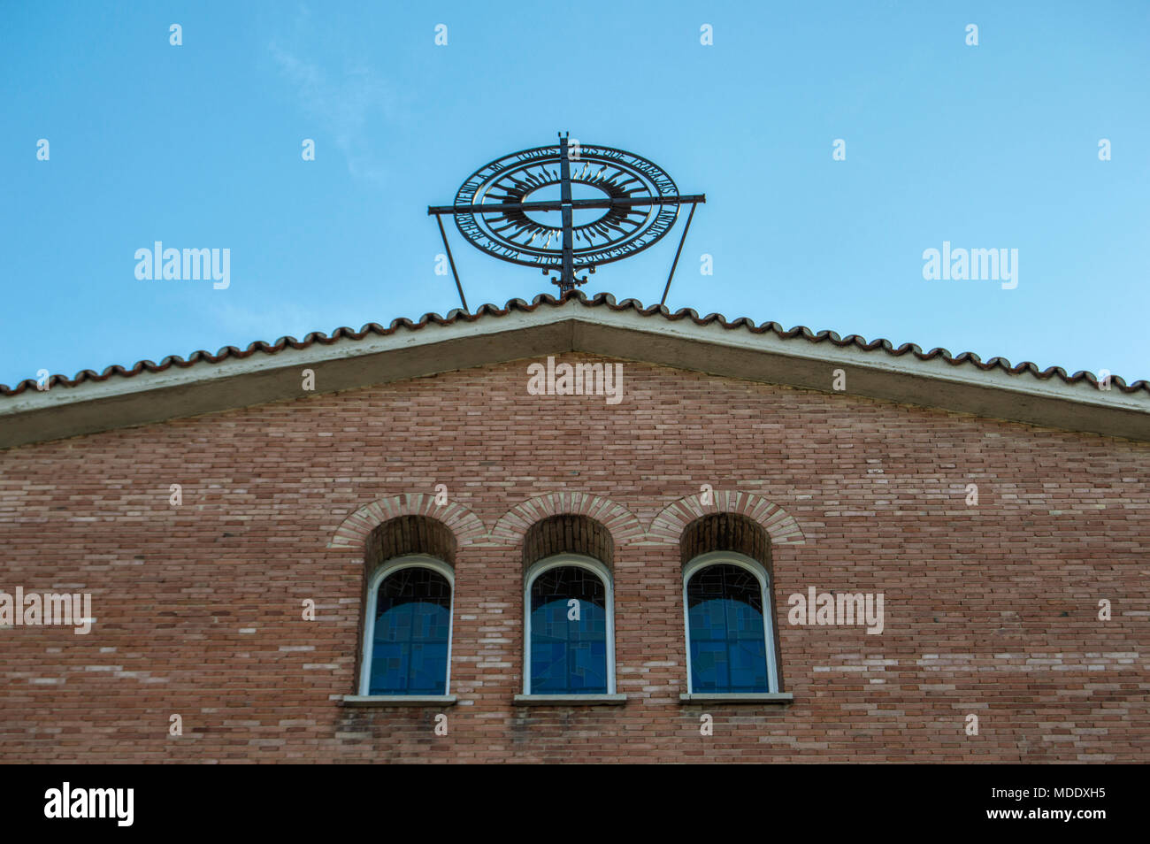 Tre strette finestre in mattone di parete esterna, con una croce di ferro sul tetto. Nella chiesa di San Vicente de Paul in Madrid. Spagna. Foto Stock