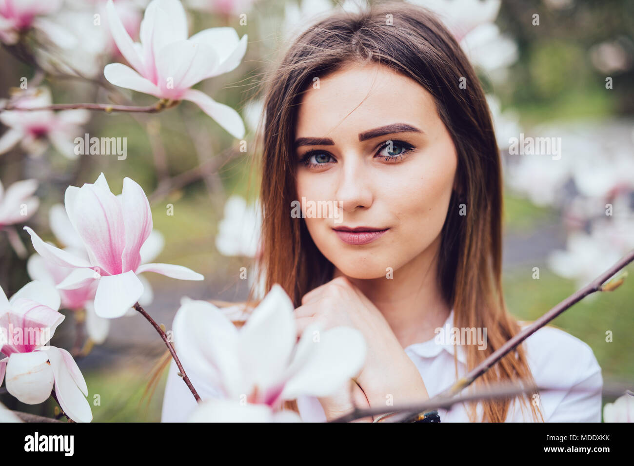 Ritratto di giovane ragazza vicino a sbocciare fiori di magnolia all'aperto nel parco di primavera Foto Stock