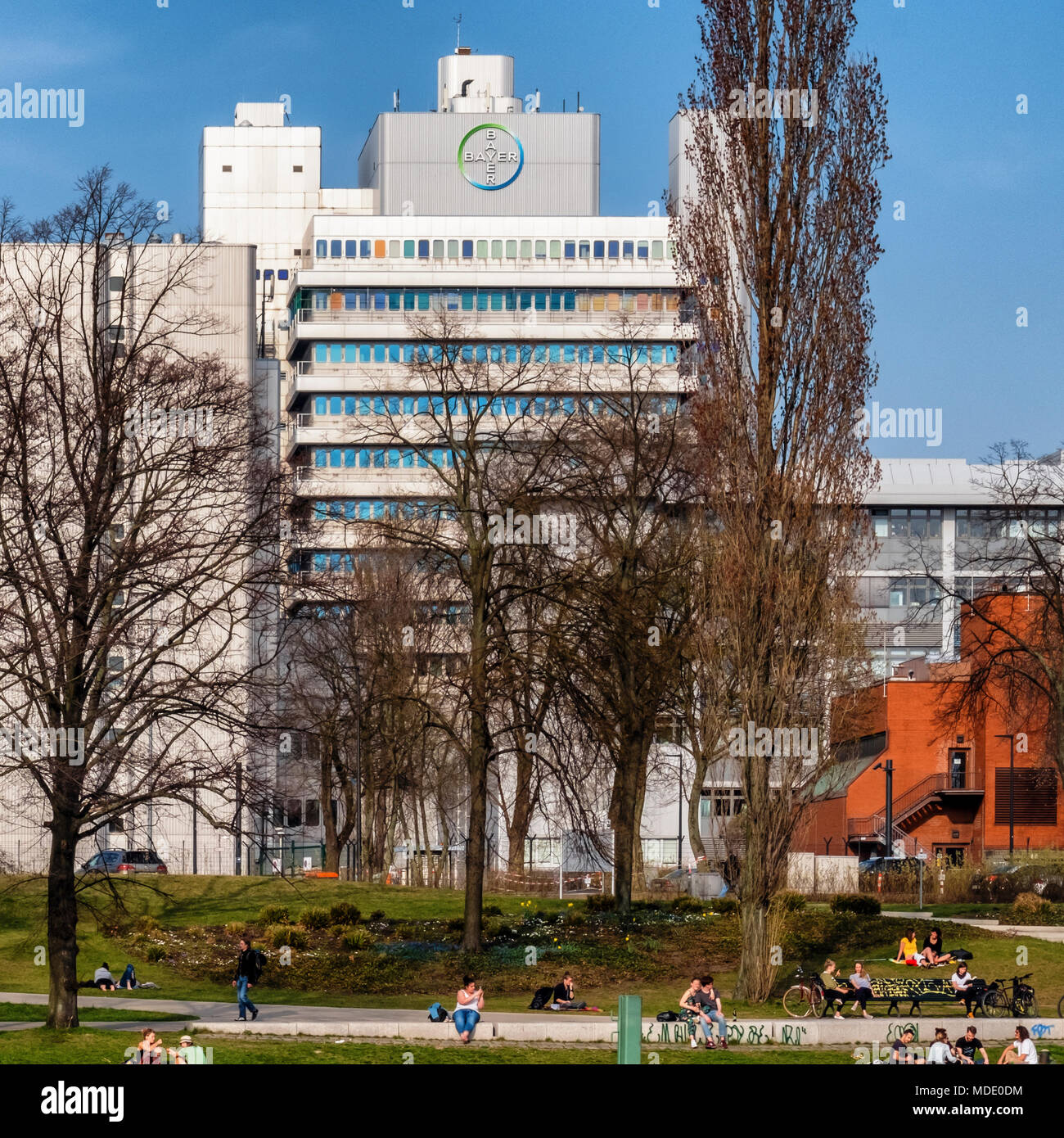 Berlin Nordhafen - Edificio con Bayer compnay farmaceutica logo accanto alla spedizione di Spandau canal & la gente seduta a waterside Foto Stock