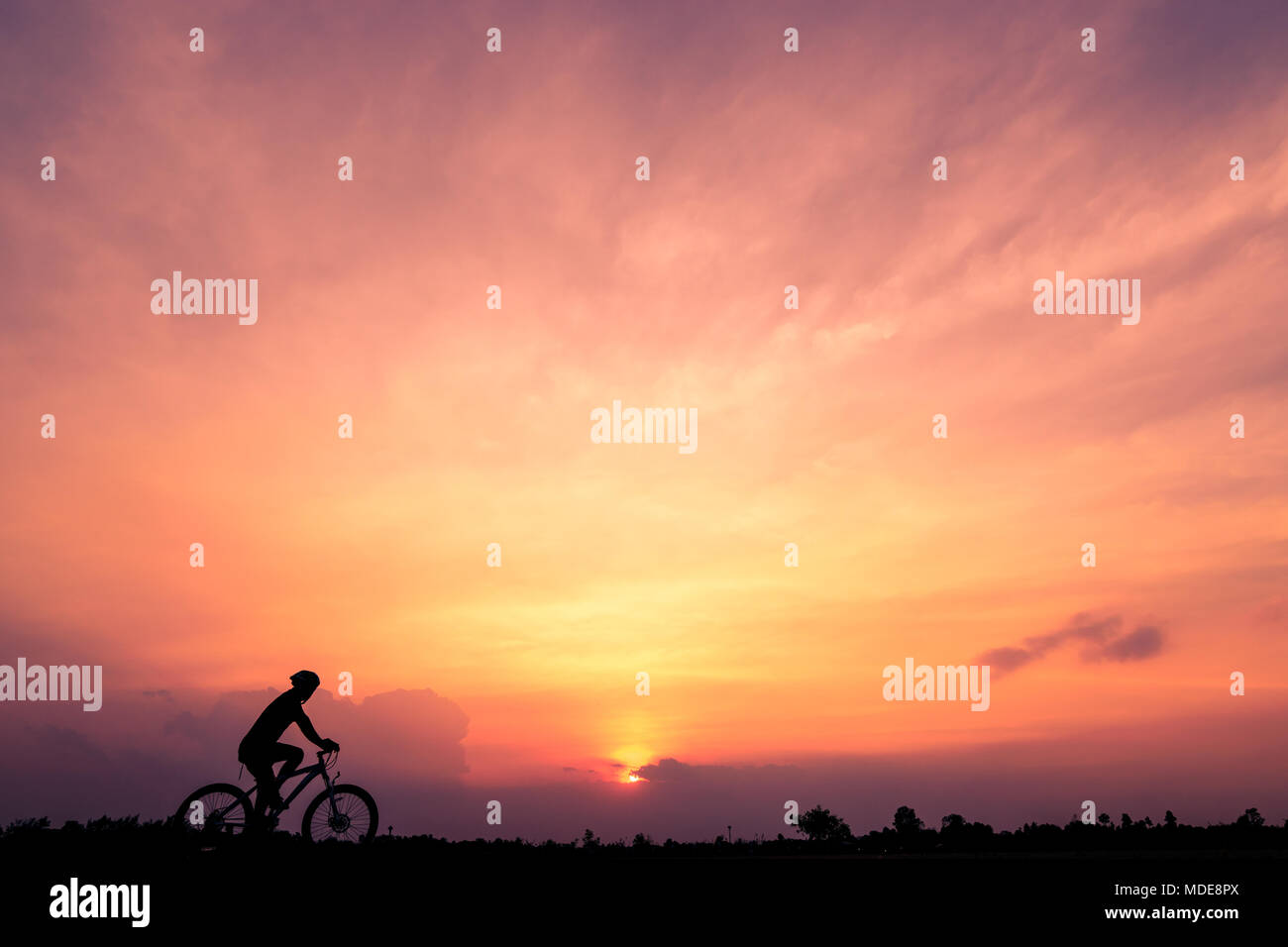 Silhouette di un ciclista guidare la bicicletta su sfondo al tramonto. Un uomo di corsa in bici su strada, lo sport e la vita attiva di concetto Foto Stock
