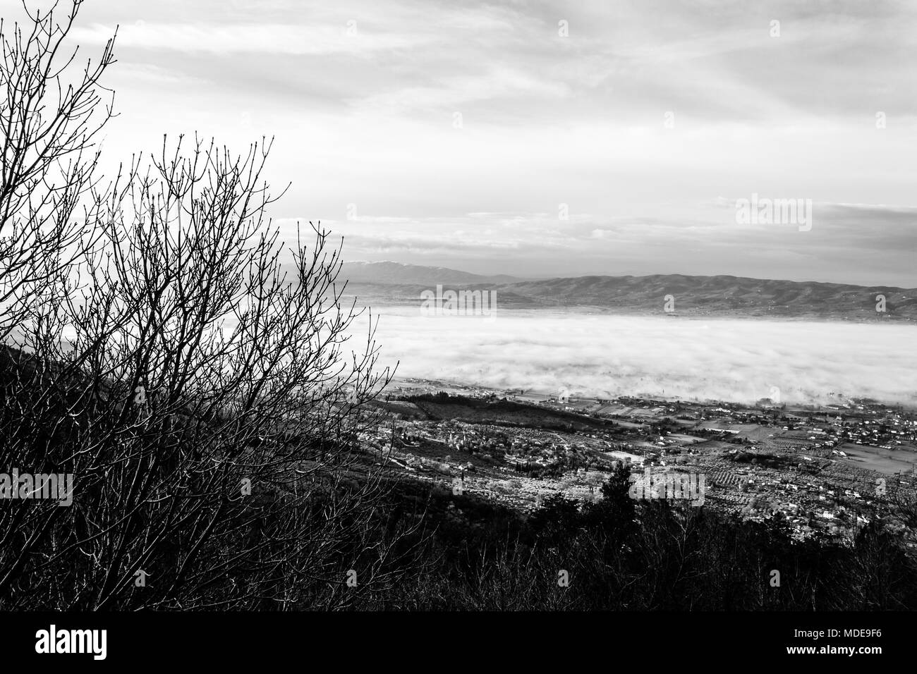 Splendida vista della valle umbra in un inverno mattina, con la nebbia che copre gli alberi e le case Foto Stock