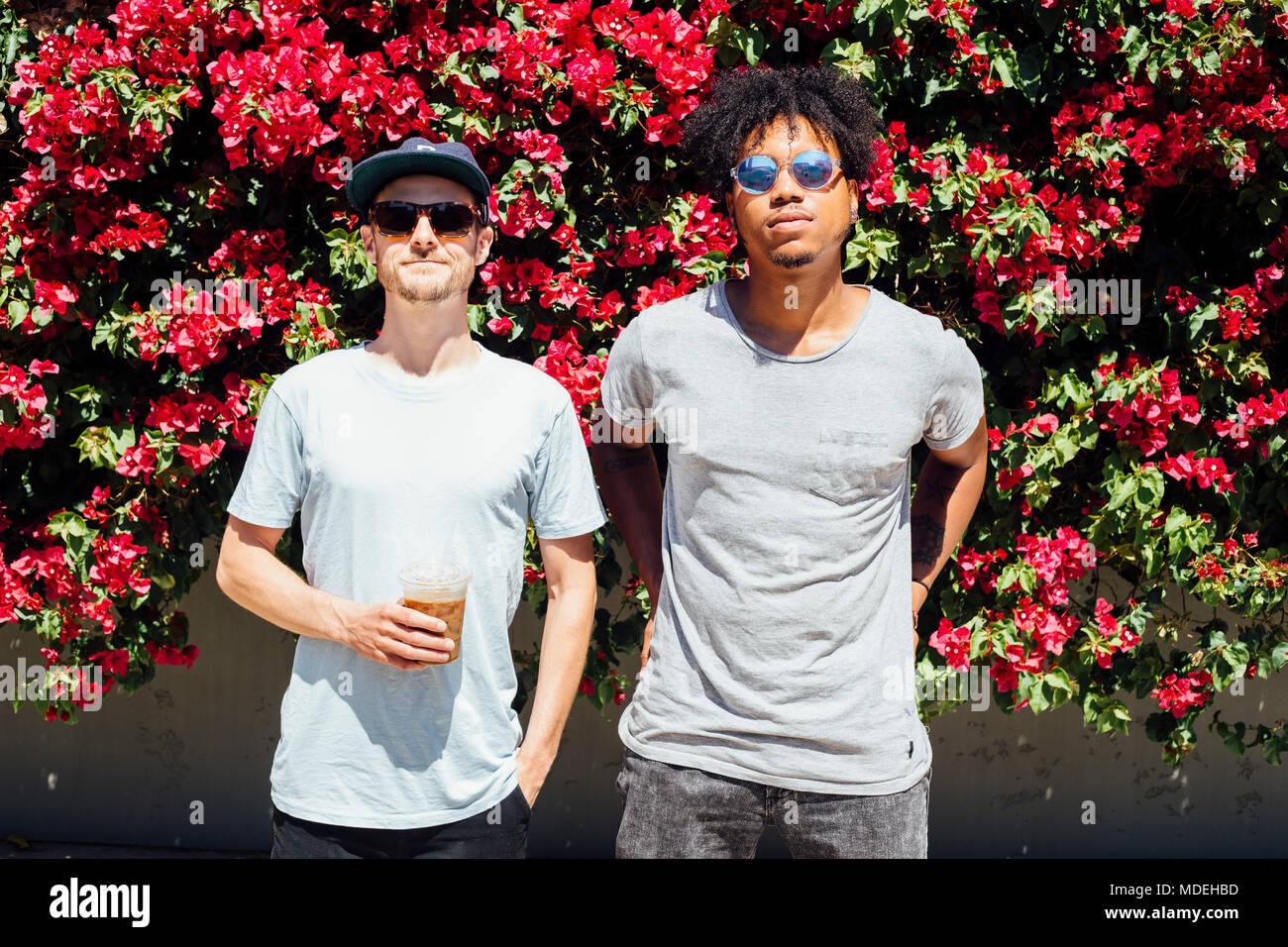 Amici in piedi accanto a ogni altra accanto a red bouganville Foto Stock
