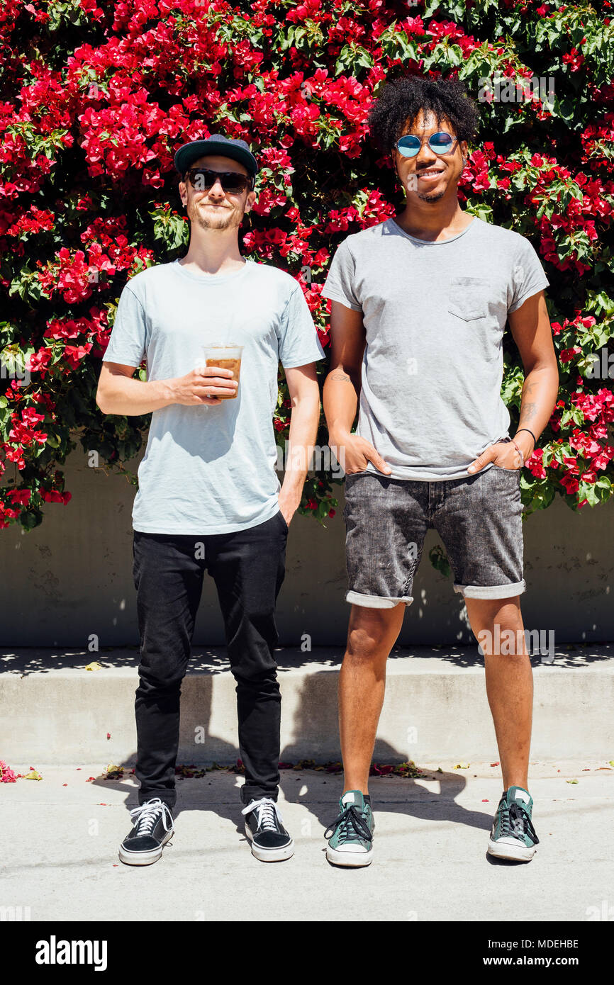 Amici in piedi accanto a ogni altra accanto a red bouganville Foto Stock