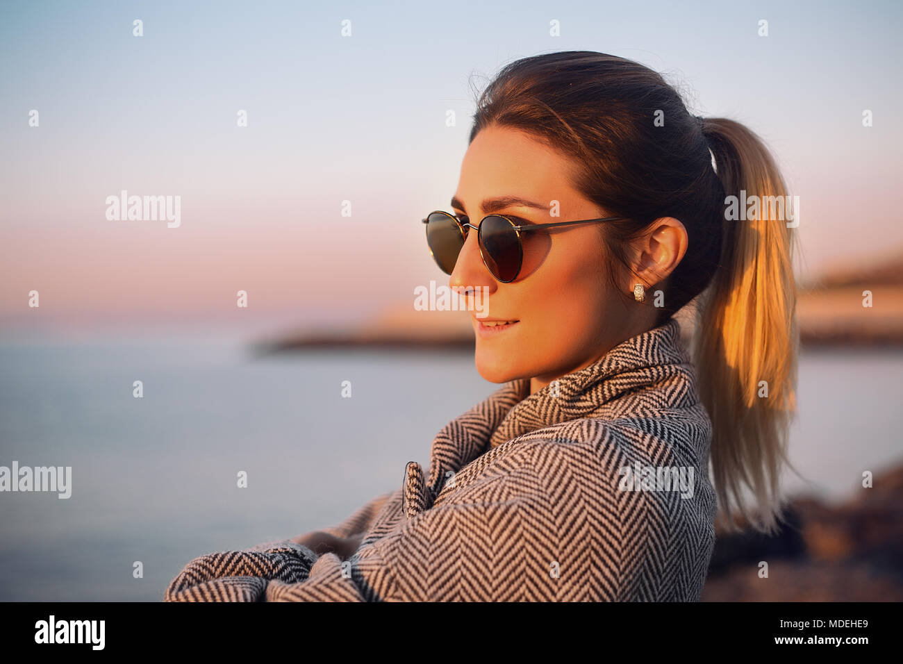 Ritratto di donna con la coda di cavallo che indossa gli occhiali da sole che guarda lontano sorridente, Odessa, Odeska Oblast, Ucraina, Europa orientale Foto Stock