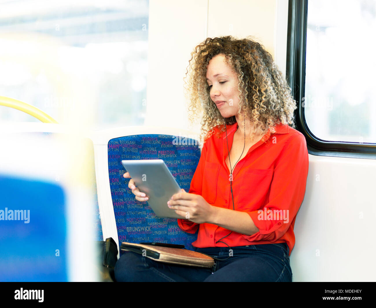 Metà donna adulta sul treno, utilizzando tavoletta digitale Foto Stock