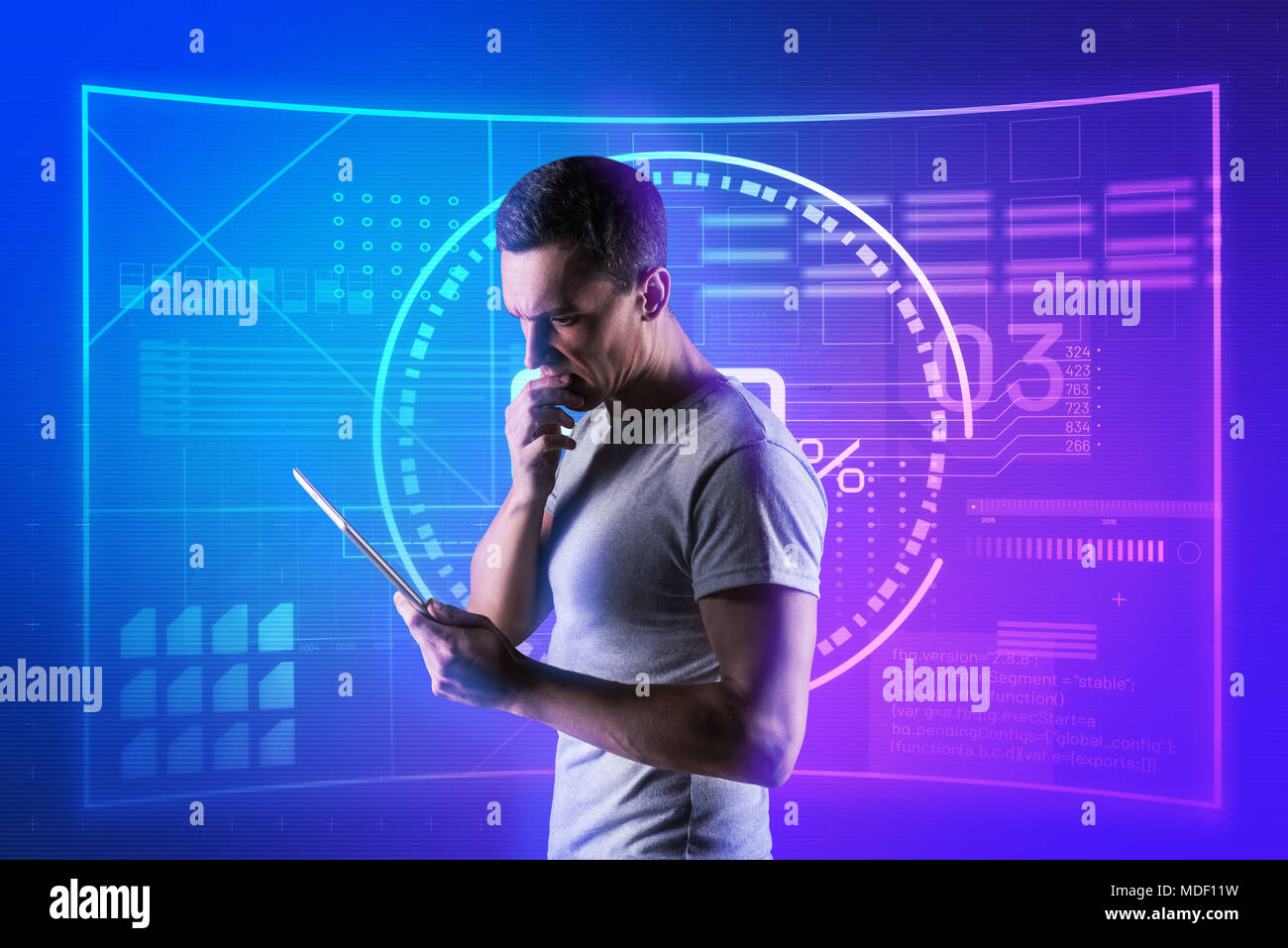 Serie software engineer pensando mentre in piedi con un moderno tablet Foto Stock