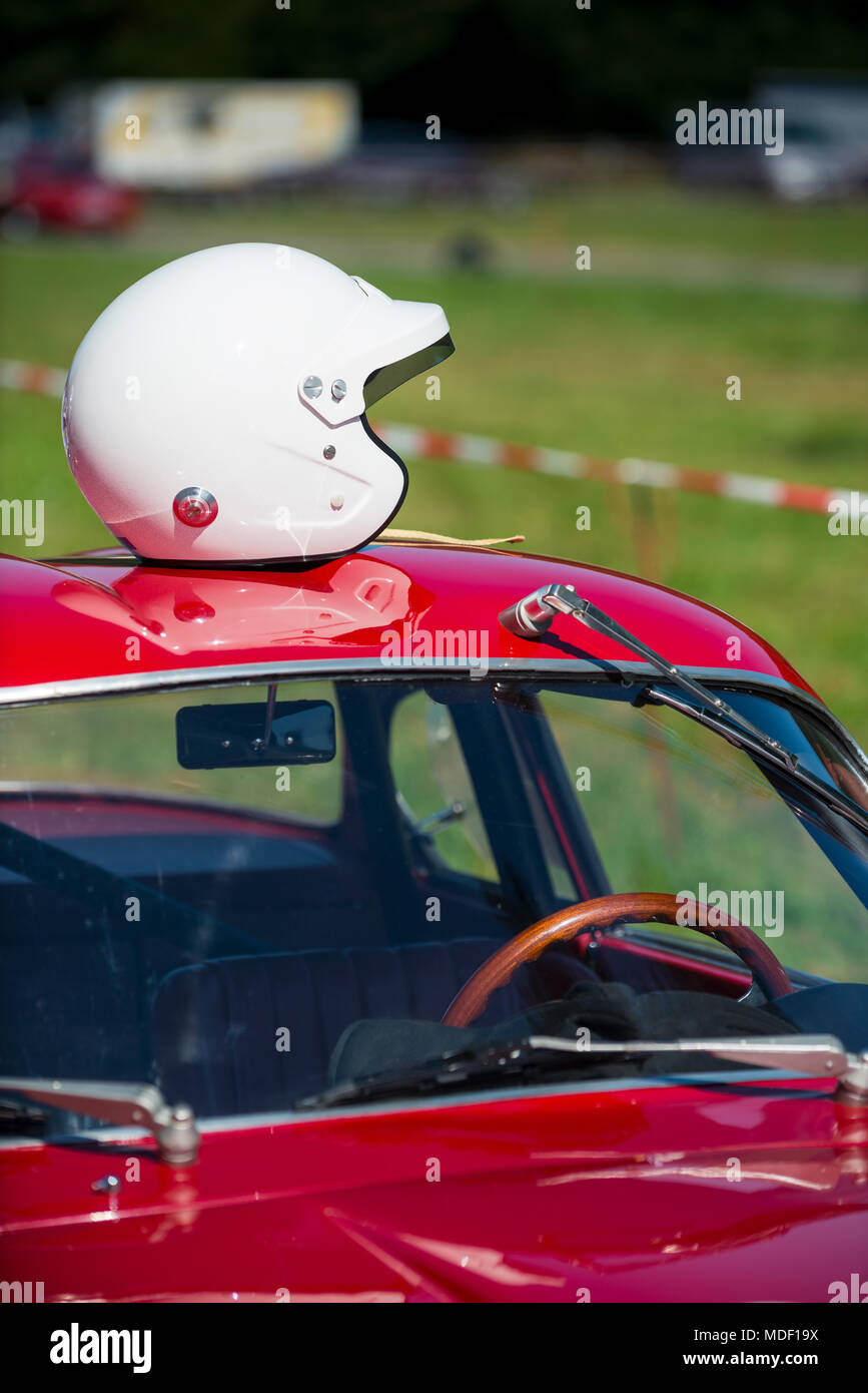 Rosso classico auto in attesa presso la buca per la grande gara con casco bianco in appoggio sul tetto della vettura Foto Stock