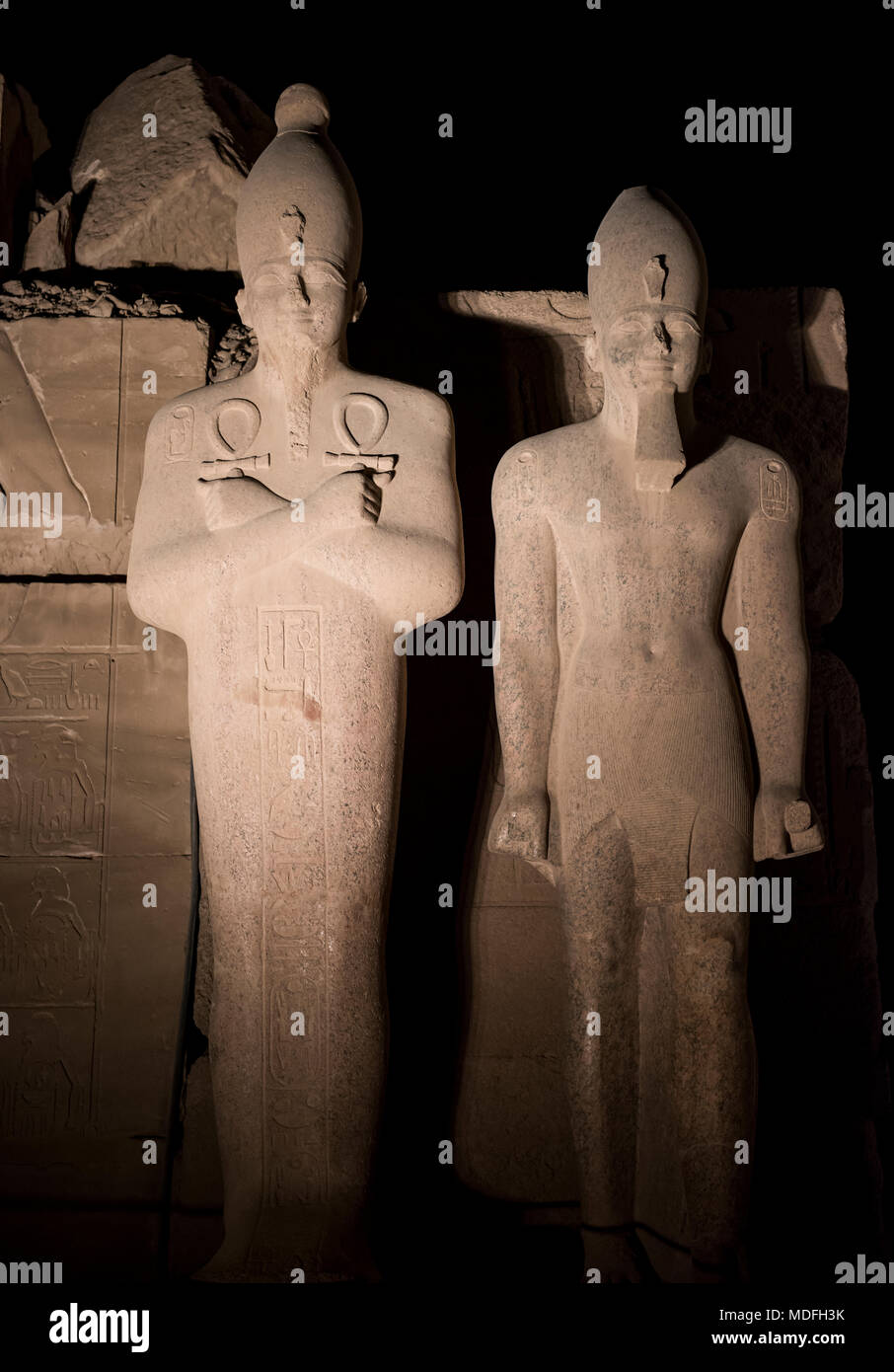 Tall pietra antiche statue egiziane al Tempio di Karnak a Luxor illuminato durante la notte sul cielo nero lo sfondo Foto Stock