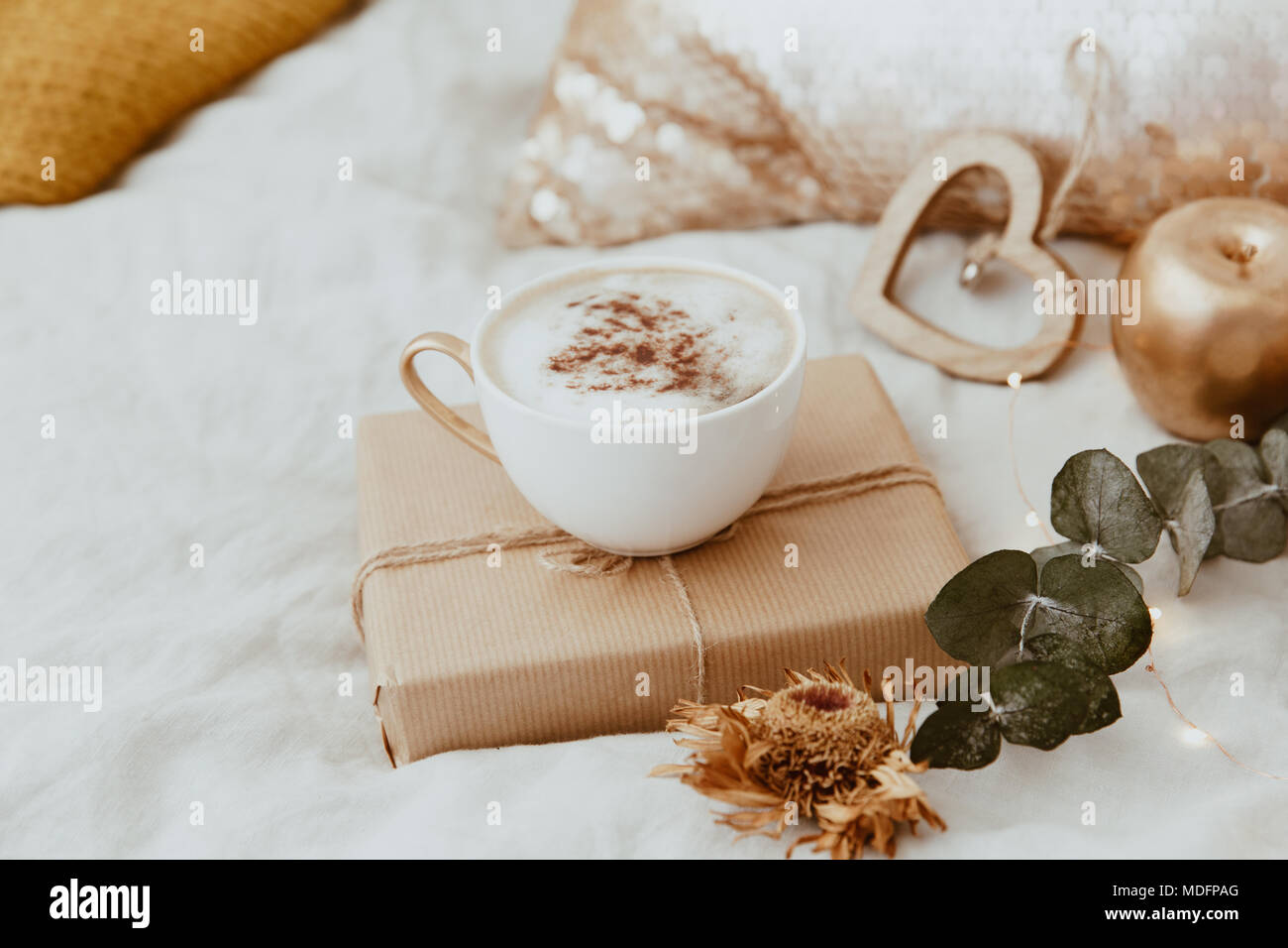 Il cappuccino e un avvolto confezione regalo su un letto Foto Stock