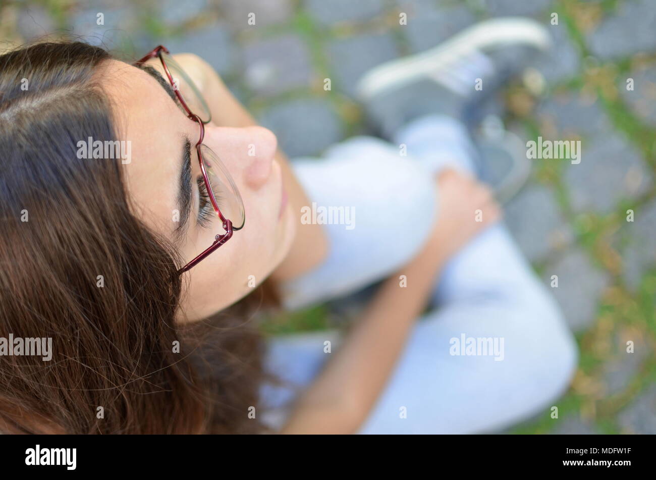 Vista aerea di una ragazza seduta sul marciapiede Foto Stock