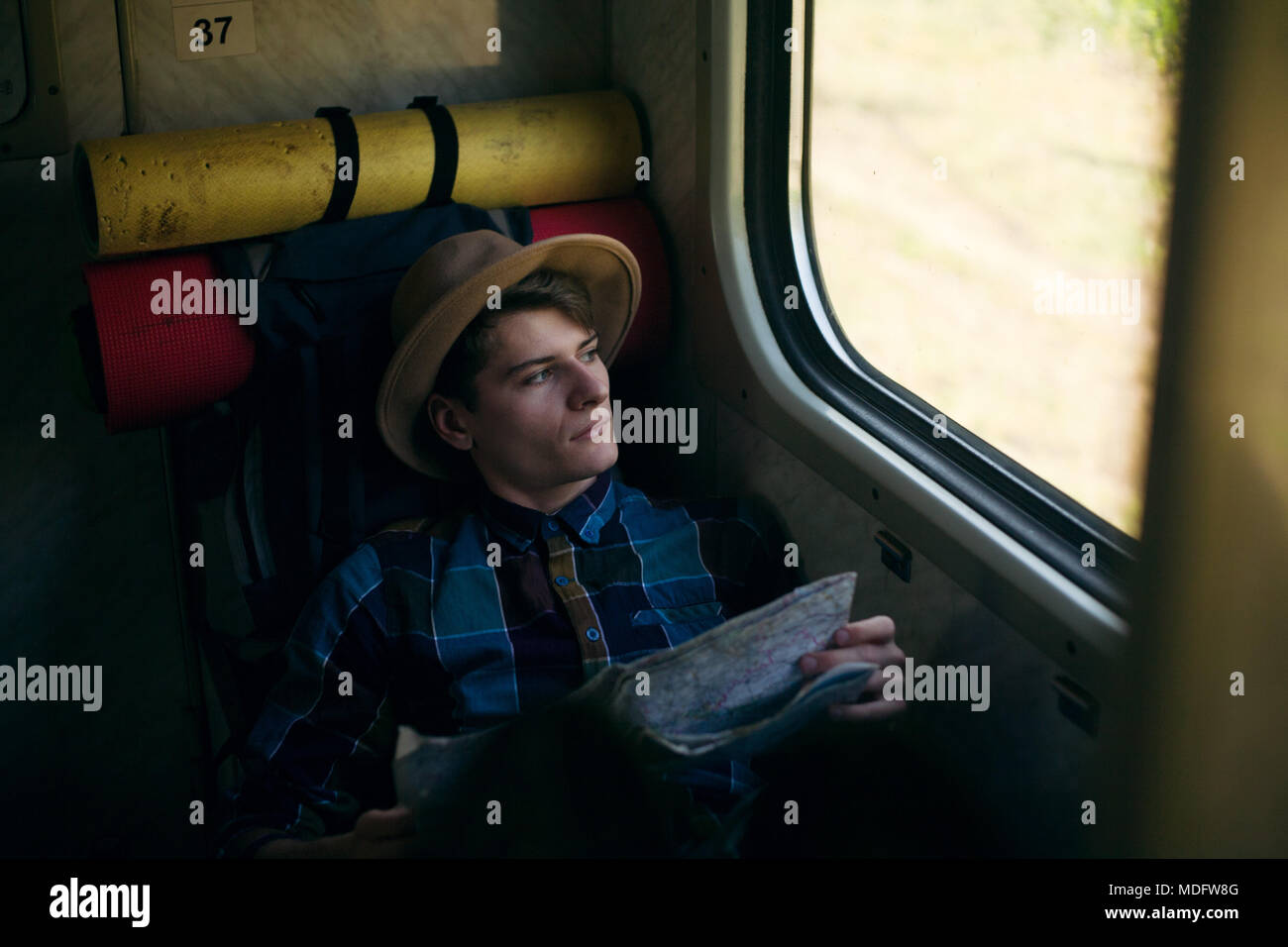 Giovane uomo ubicazione su un treno con una mappa Foto Stock