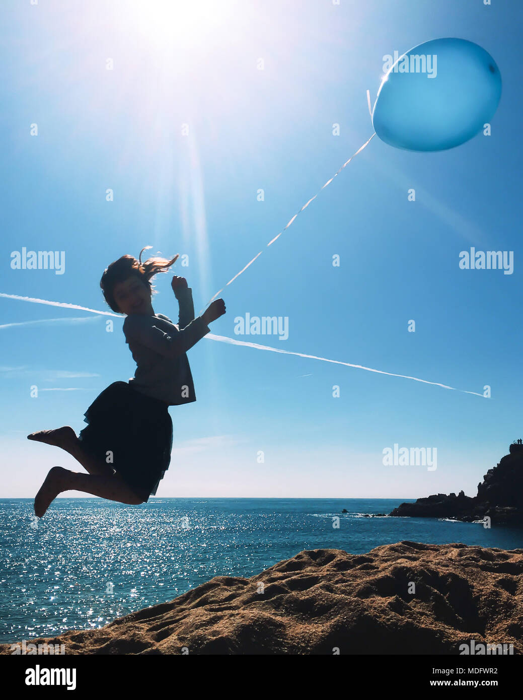 Silhouette di una ragazza con un palloncino di saltare in aria per la spiaggia Foto Stock