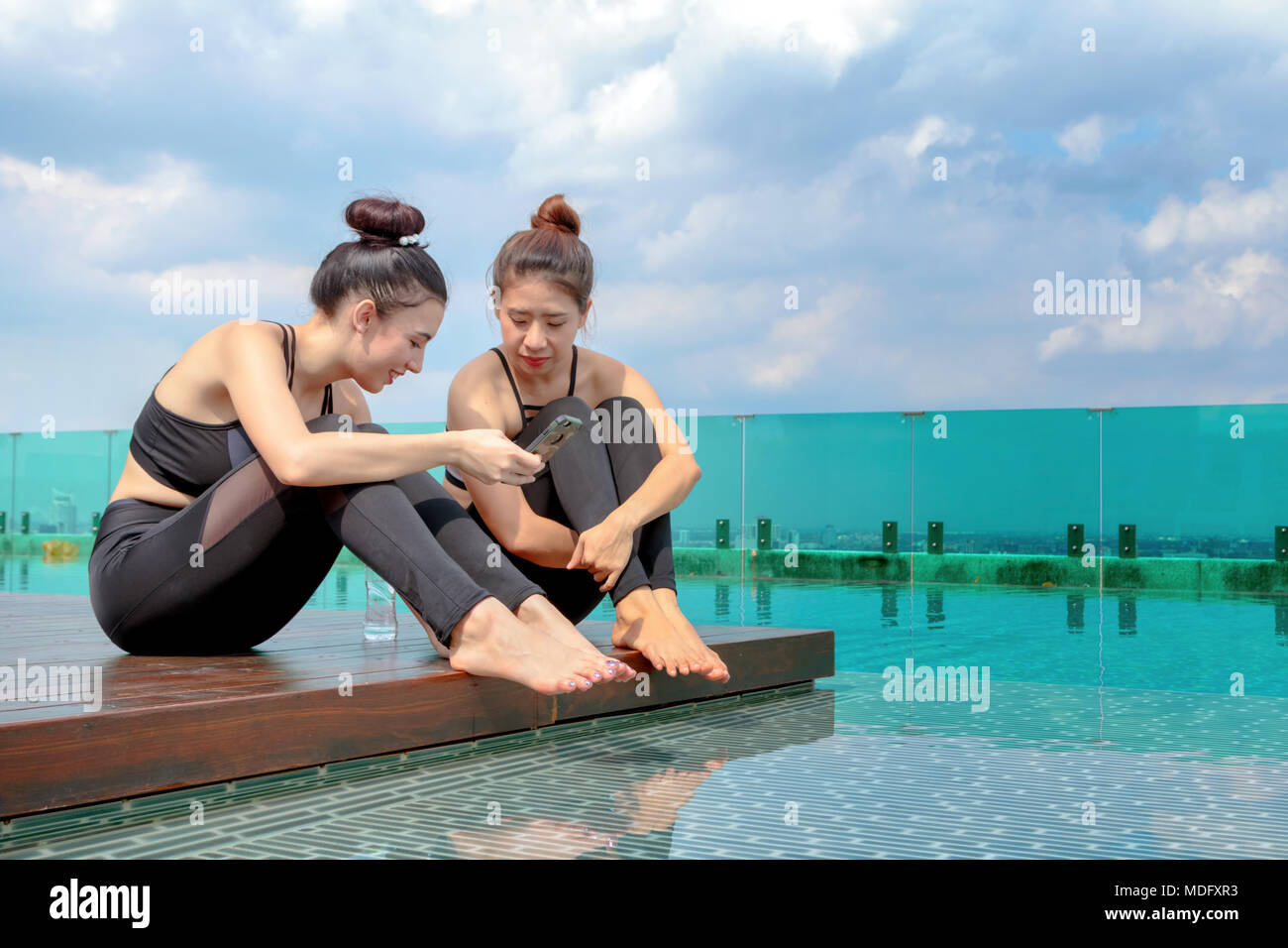 Lo stile di vita di vacanza di giovani donne che utilizzano tablet pc seduti in piscina dopo il lavoro fuori Foto Stock