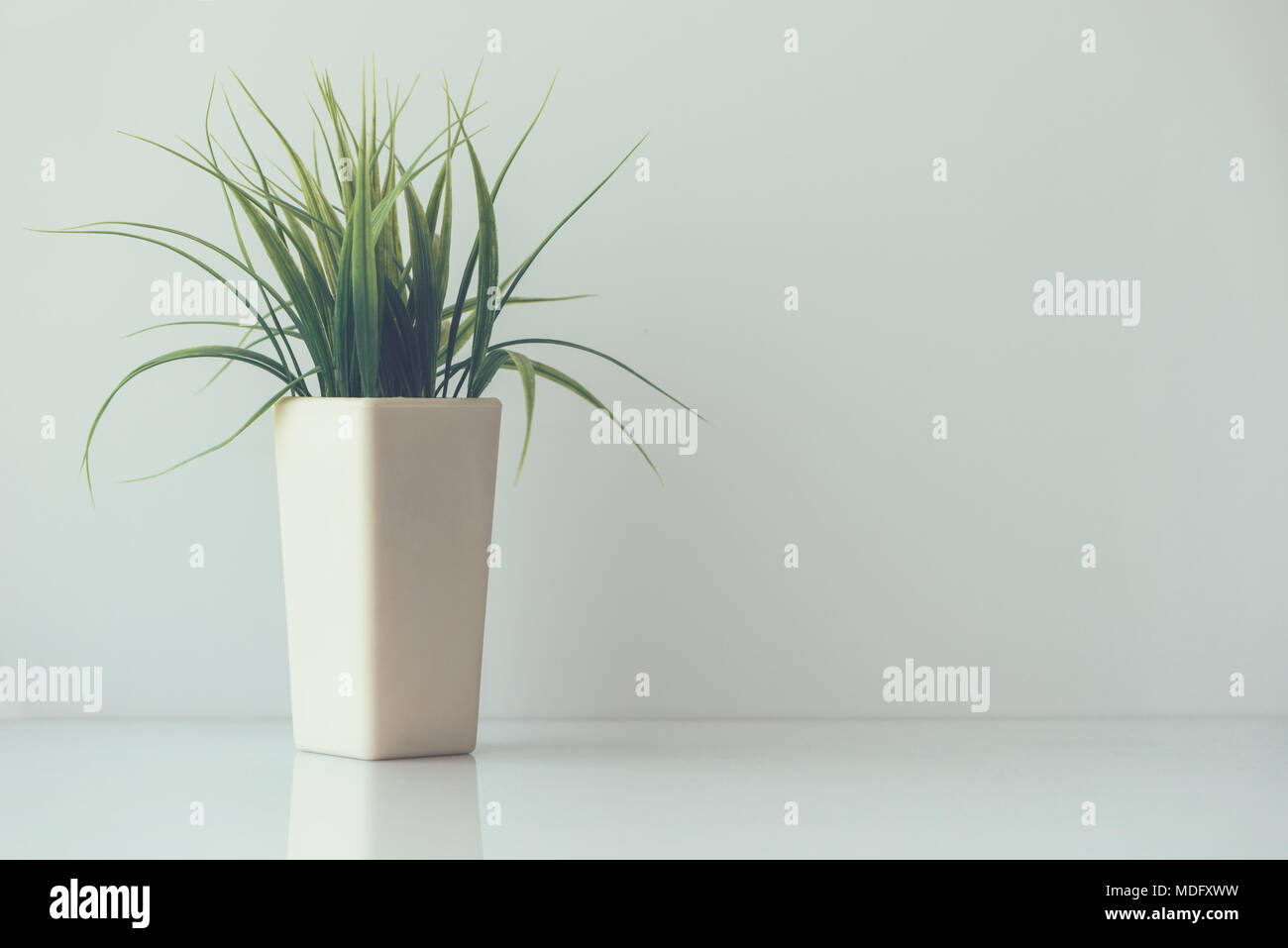 Composizione minimalista - fiore di plastica in una pentola con vuoto bianco spazio di copia Foto Stock