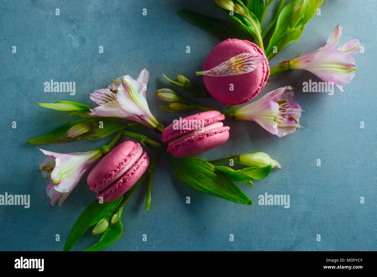 Amaretti rosa decorata con rosa e bianco fiori alstroemeria. Romantico francese dessert su sfondo di pietra con copia spazio. Foto Stock