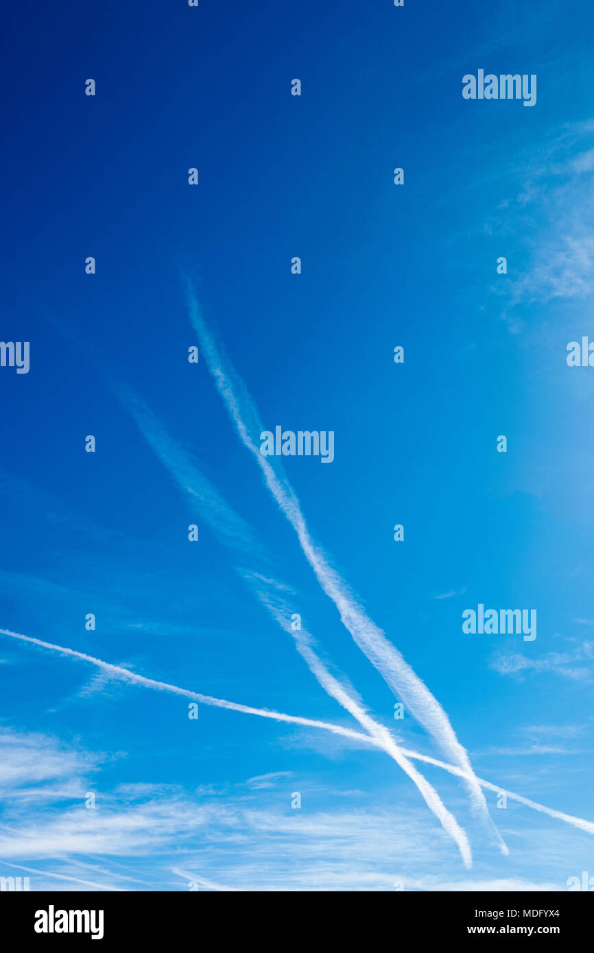 Jet bianco contrails contro un cristallo azzurro cielo azzurro Foto Stock