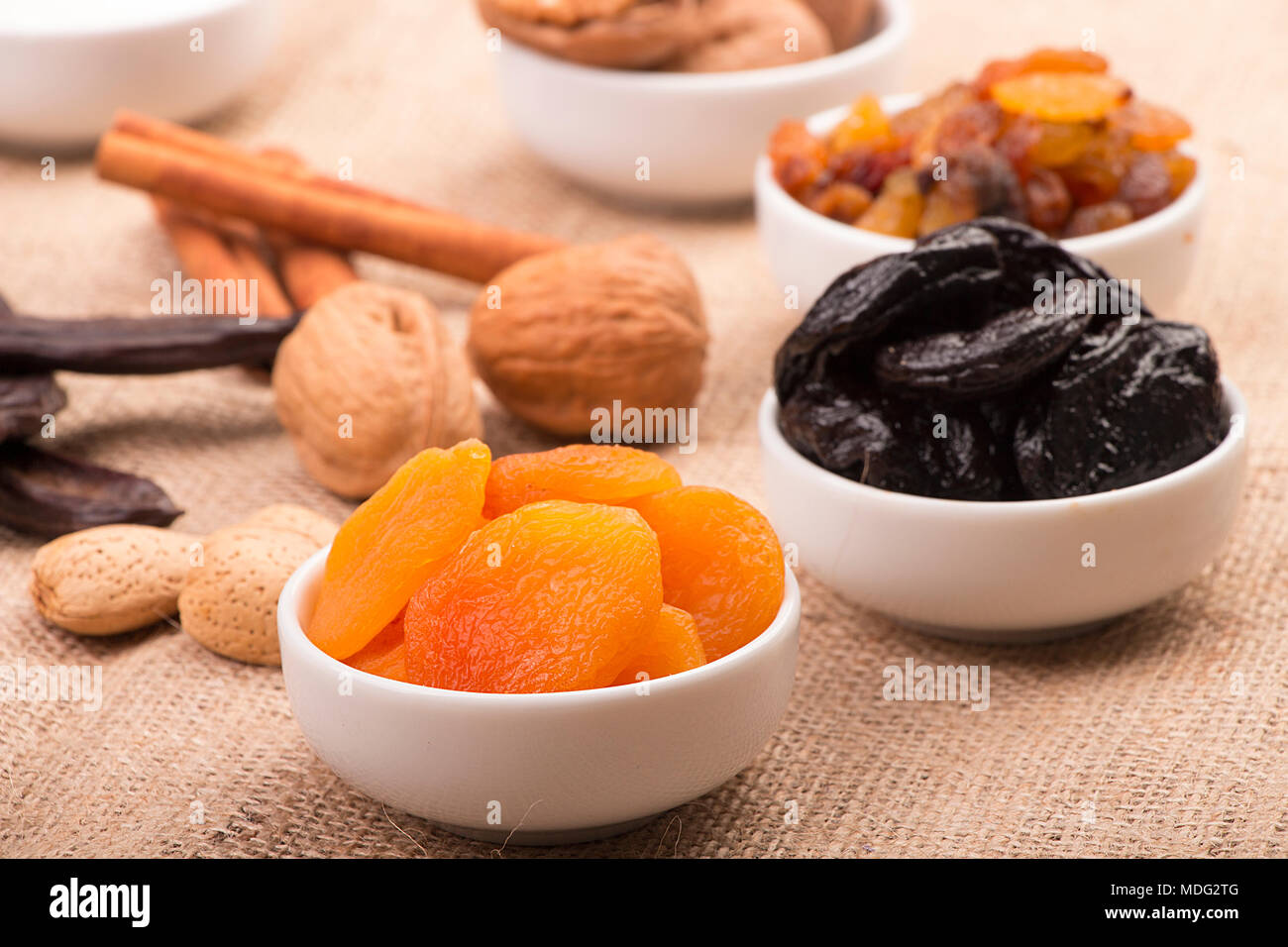 Mix di Ramadan dolci - frutta secca e noci ( albicocche, prugne e uvetta, noci, nocciole, mandorle, carruba e cannella) su un letto di sacco sullo sfondo Foto Stock