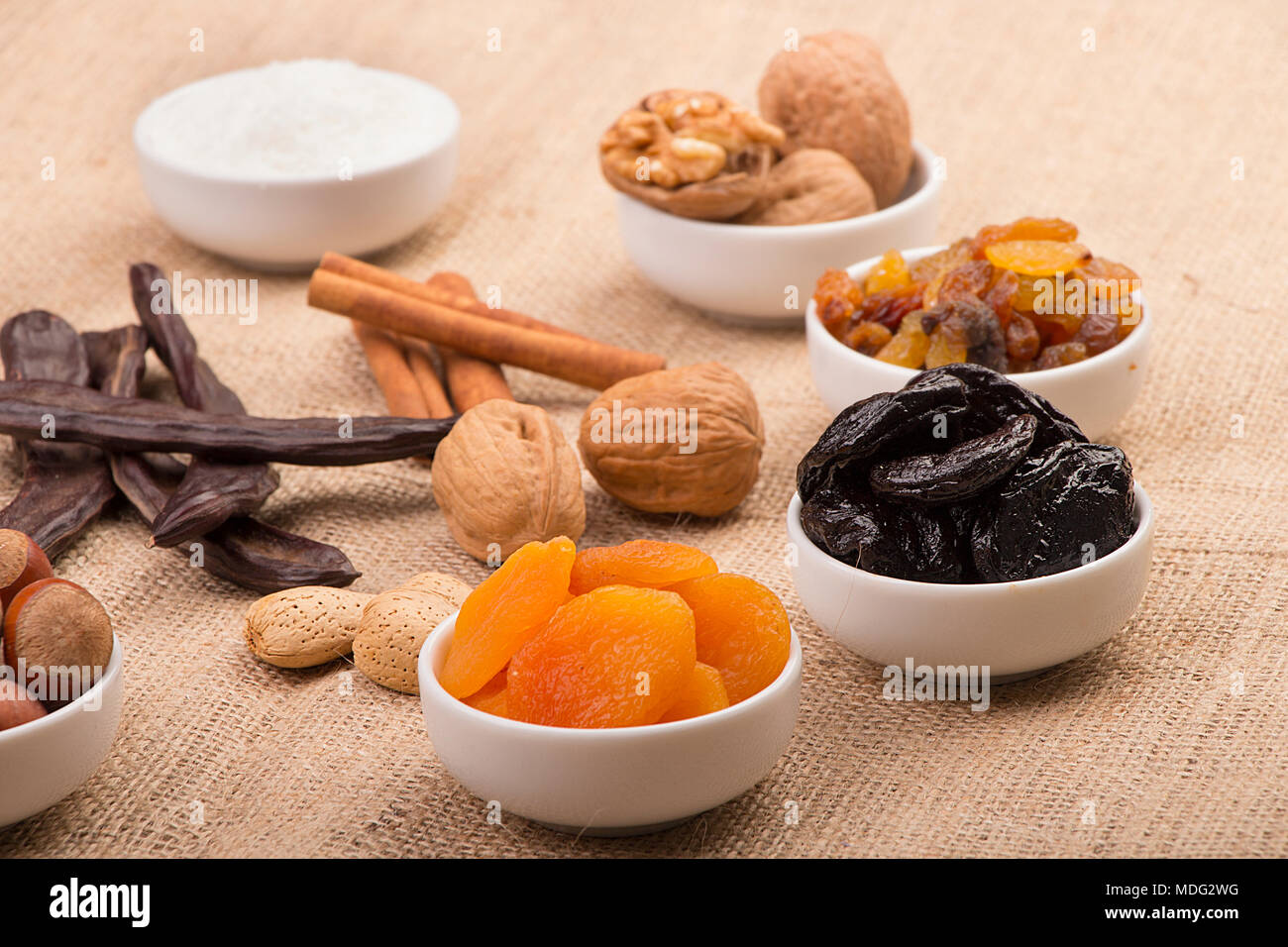 Mix di Ramadan dolci - frutta secca e noci ( albicocche, prugne e uvetta, noci, nocciole, mandorle, carruba e cannella) su un letto di sacco sullo sfondo Foto Stock