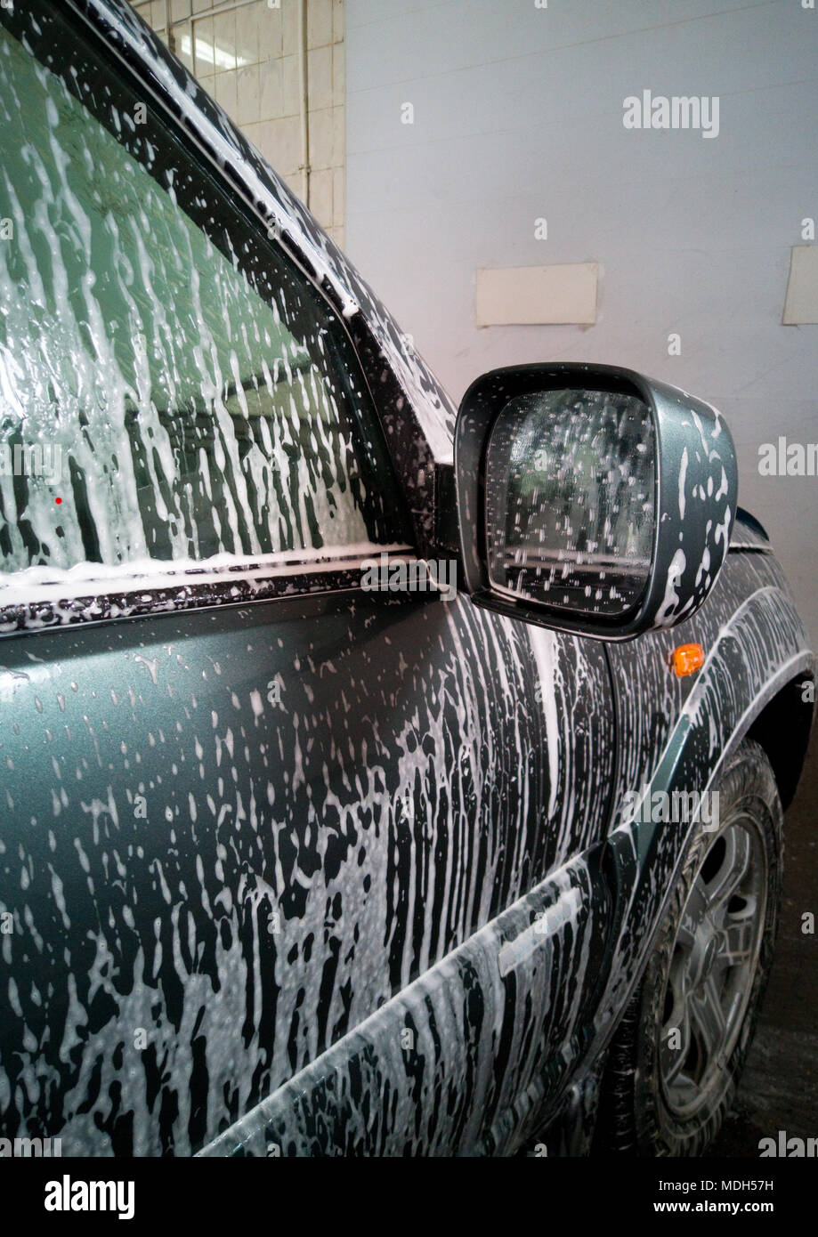 Car Wash. La schiuma fluisce verso il basso e si scioglie lo sporco sulla porta di destra e la vettura specchietto retrovisore. Foto Stock
