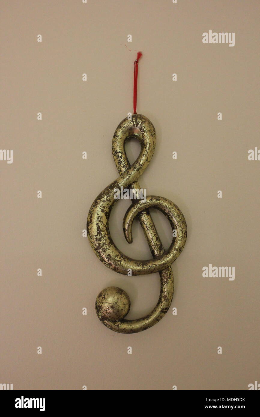 Metallico decorativo musica simbolo di costo appeso a una parete in uno studio musicale. Foto Stock