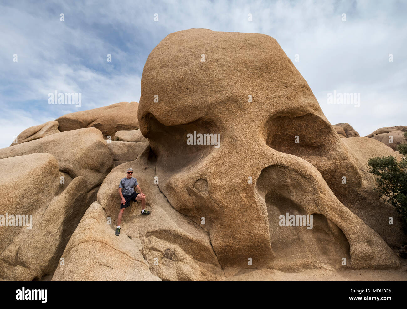 Un anziano uomo si arrampica Skull Rock a Joshua Tree National Park, California, Stati Uniti d'America Foto Stock