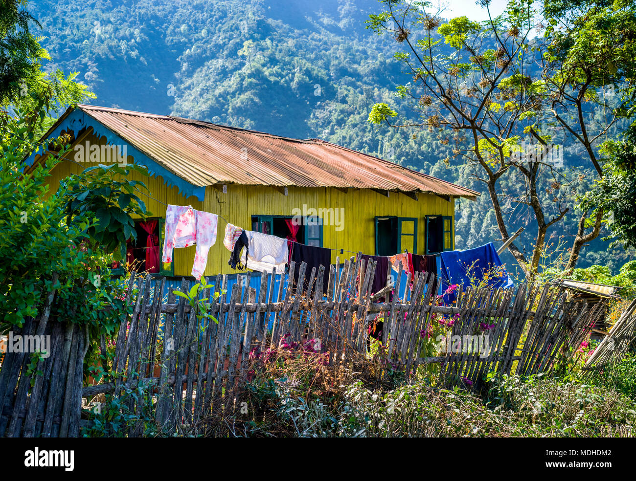 Una luminosa casa gialla con rivestimento blu e uno stendibiancheria appeso al di fuori dell'Himalaya; West Bengal, India Foto Stock