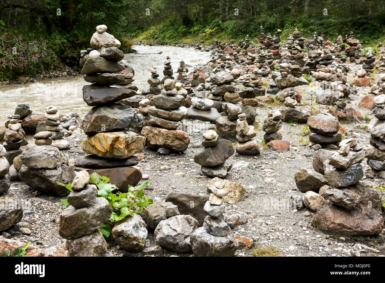 Numerose impilati rock sculture lungo una riva di un fiume; Grainau, Baviera, Germania Foto Stock