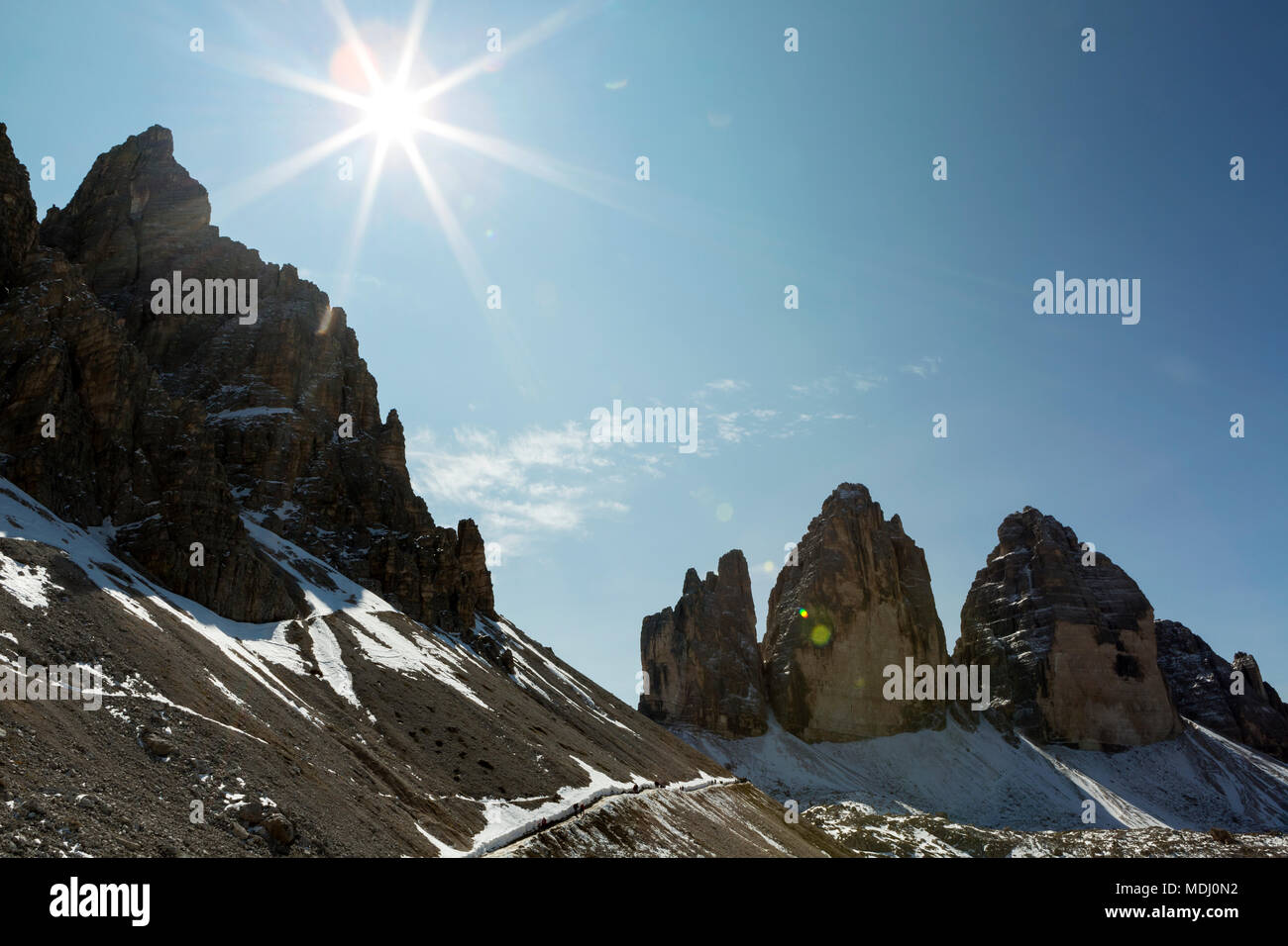 Robusto guglie di montagna con sunburst e cielo blu; Sesto, Bolzano, Italia Foto Stock