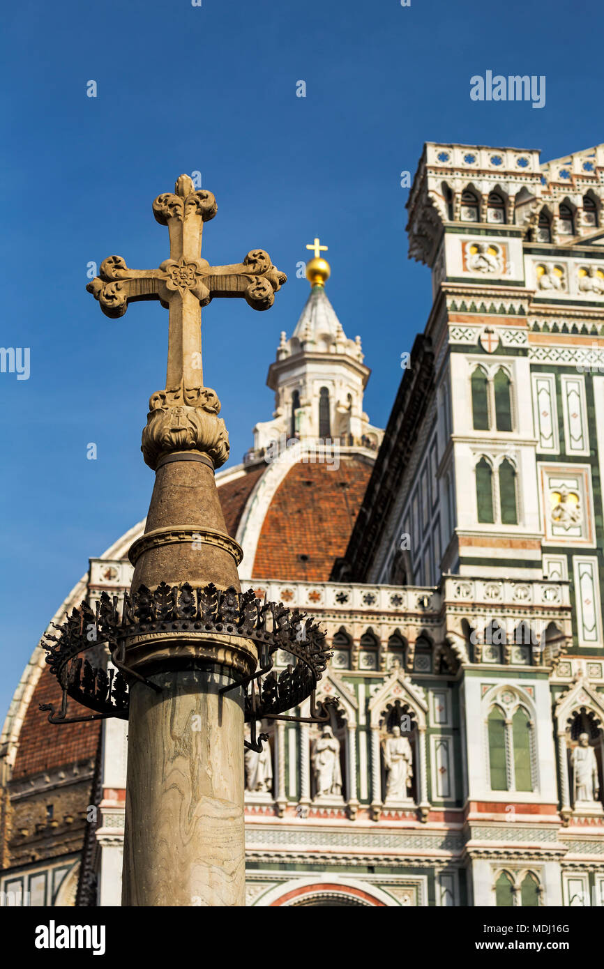 Croce di pietra con la cupola decorativa e la facciata del Duomo di Firenze con il blu del cielo; Firenze, Toscana, Italia Foto Stock
