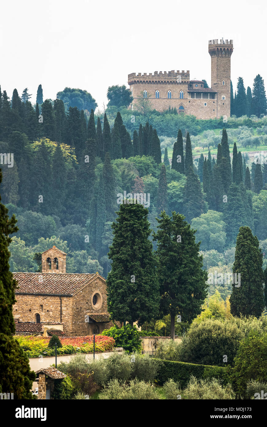 Collina coperta da alberi nella nebbia e una chiesa di pietra nella valle e il castello sulla collina; Italia Foto Stock