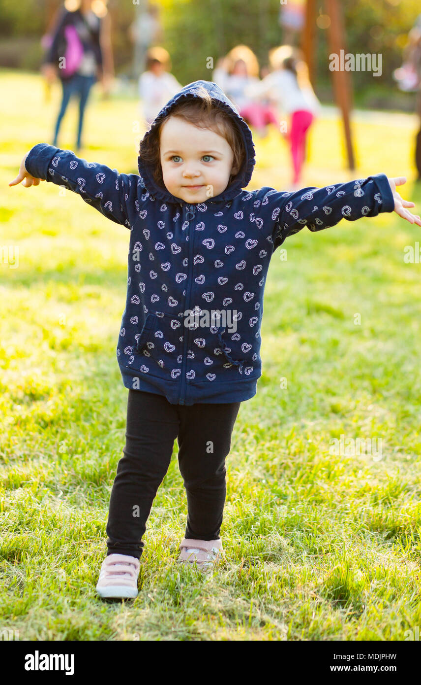 Piccola bambina gioca felice nel parco all'aperto nella primavera in controluce. Foto Stock