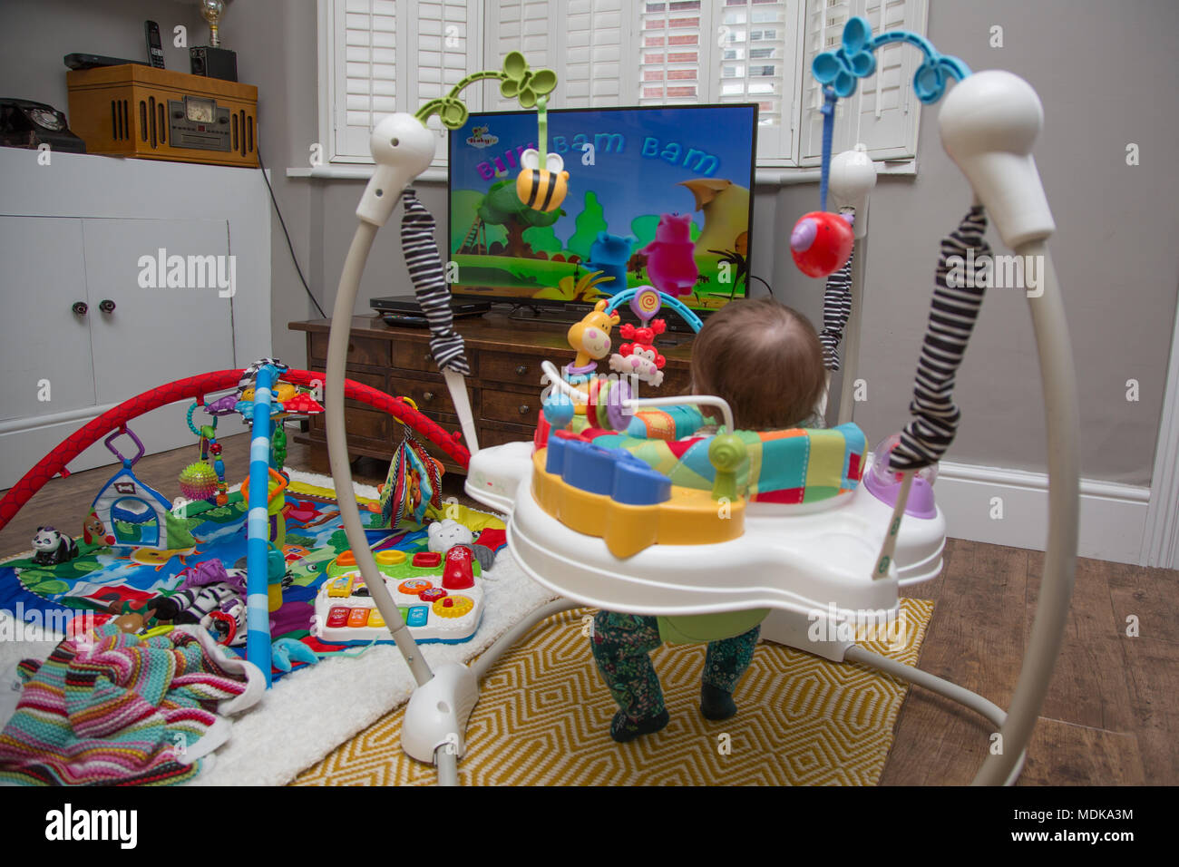 Bambino in jumperoo guardare la televisione Foto Stock