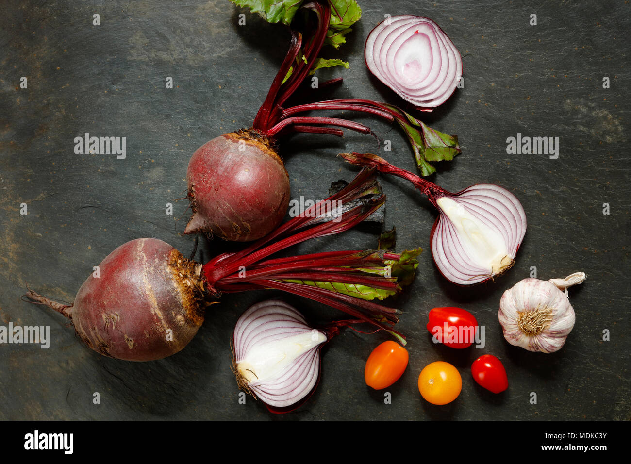 Fresco intero di barbabietole con cipolle rosse , aglio e i pomodori ciliegia sulla tavola di ardesia con spazio di copia Foto Stock
