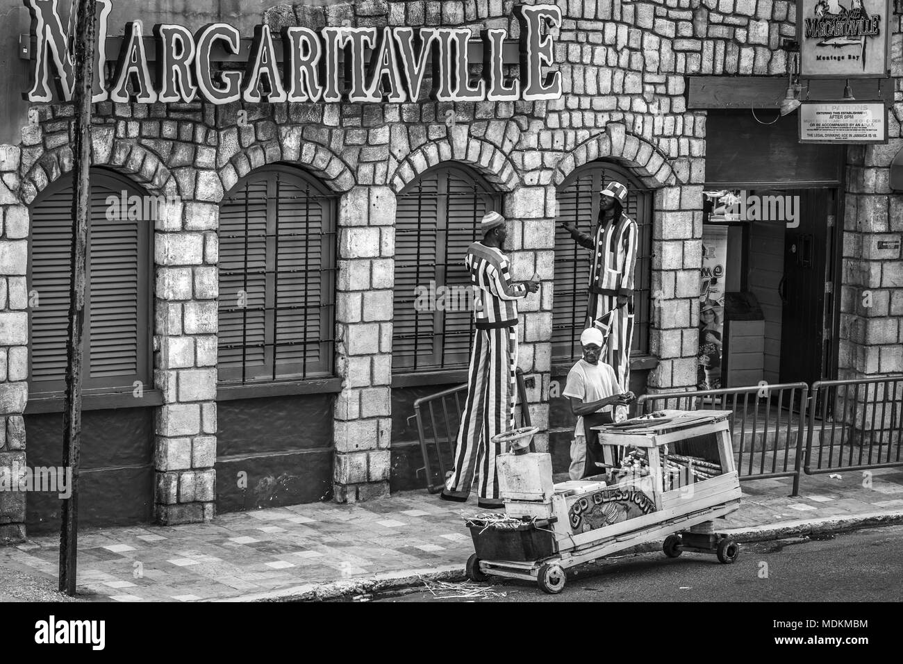 Tall mascotte per intrattenere i turisti e una frutta fresca fornitore infront permanente del buffet del Jimmy Margaritaville Montego Bay in Giamaica Foto Stock