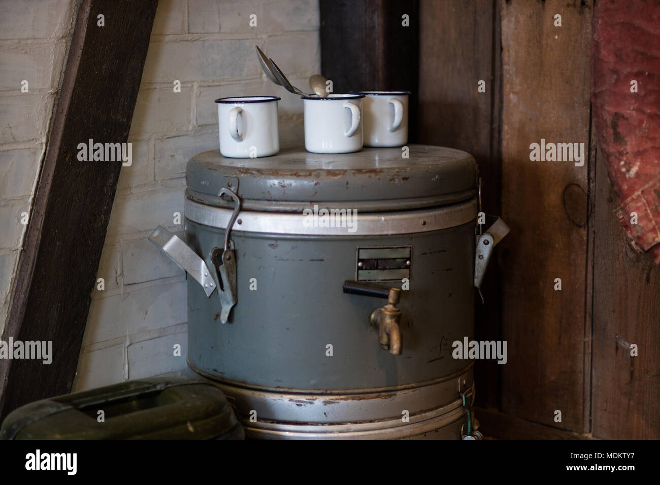 Antico e grande thermos per le bevande con un rubinetto e tazze. Accessori da cucina per la nutrizione collettiva. Stilizzata interni. Foto Stock