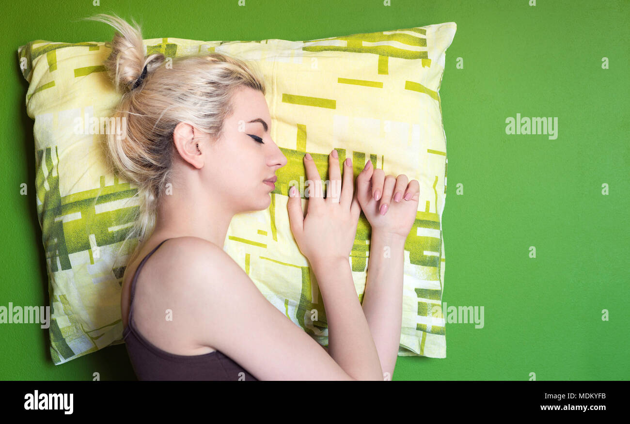 Giovane donna che dorme sul cuscino verde e lo sfondo Foto Stock