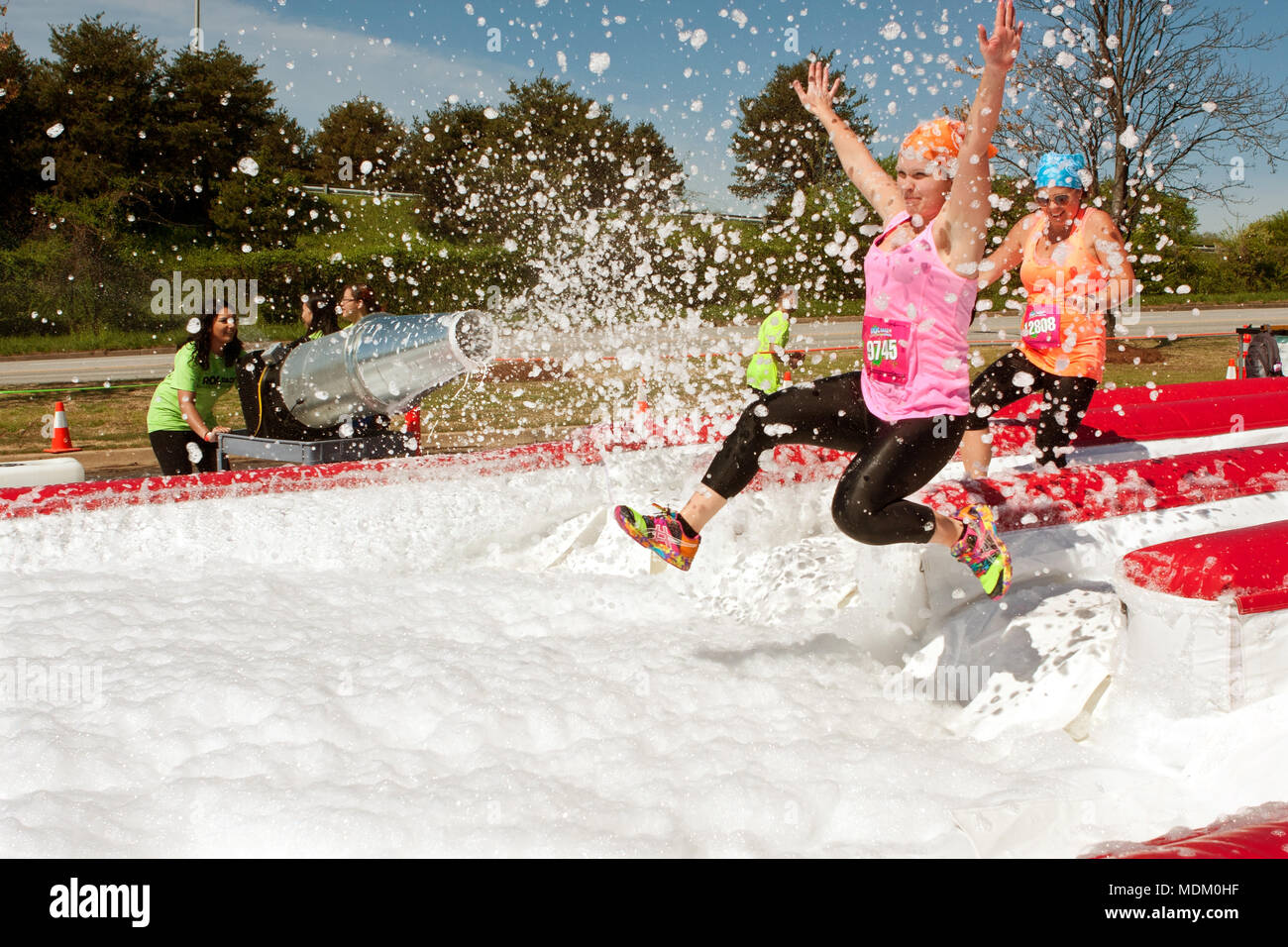 Giovani donne ottenere spruzzata con bolle salto in una fossa di schiuma, che prendono parte al ridicolo ostacolo sfida su Aprile 5, 2014 in Atlanta, GA. Foto Stock