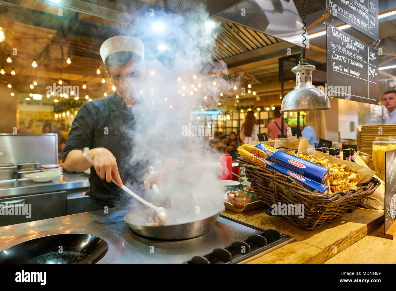 SAINT PETERSBURG, Russia - circa agosto, 2017: uomo sapientemente preparare il cibo in un wok Marketplace al ristorante. Foto Stock