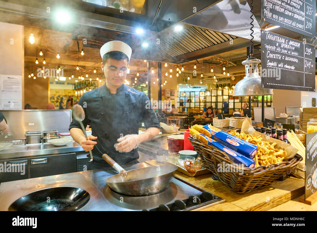 SAINT PETERSBURG, Russia - circa agosto, 2017: uomo sapientemente preparare il cibo in un wok Marketplace al ristorante. Foto Stock