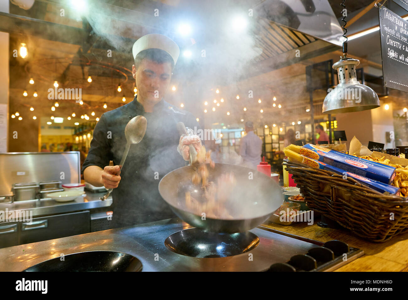 SAINT PETERSBURG, Russia - circa agosto, 2017: uomo sapientemente preparare il cibo in un wok Marketplace al ristorante. Foto Stock