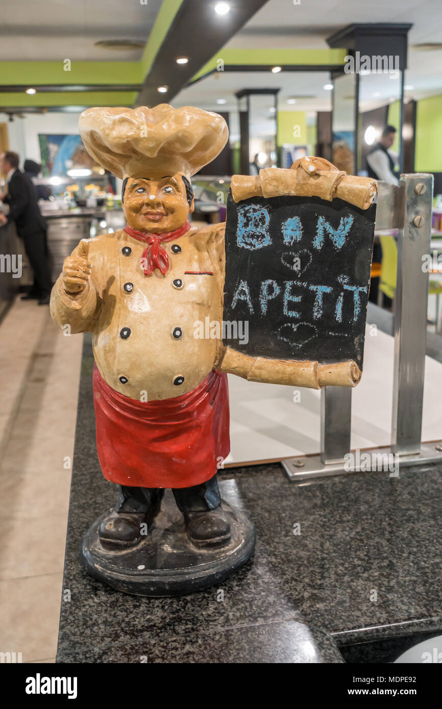 Una figura di uno chef fatta di ceramica tenendo un bordo nero con il messaggio bon apetit. Foto Stock