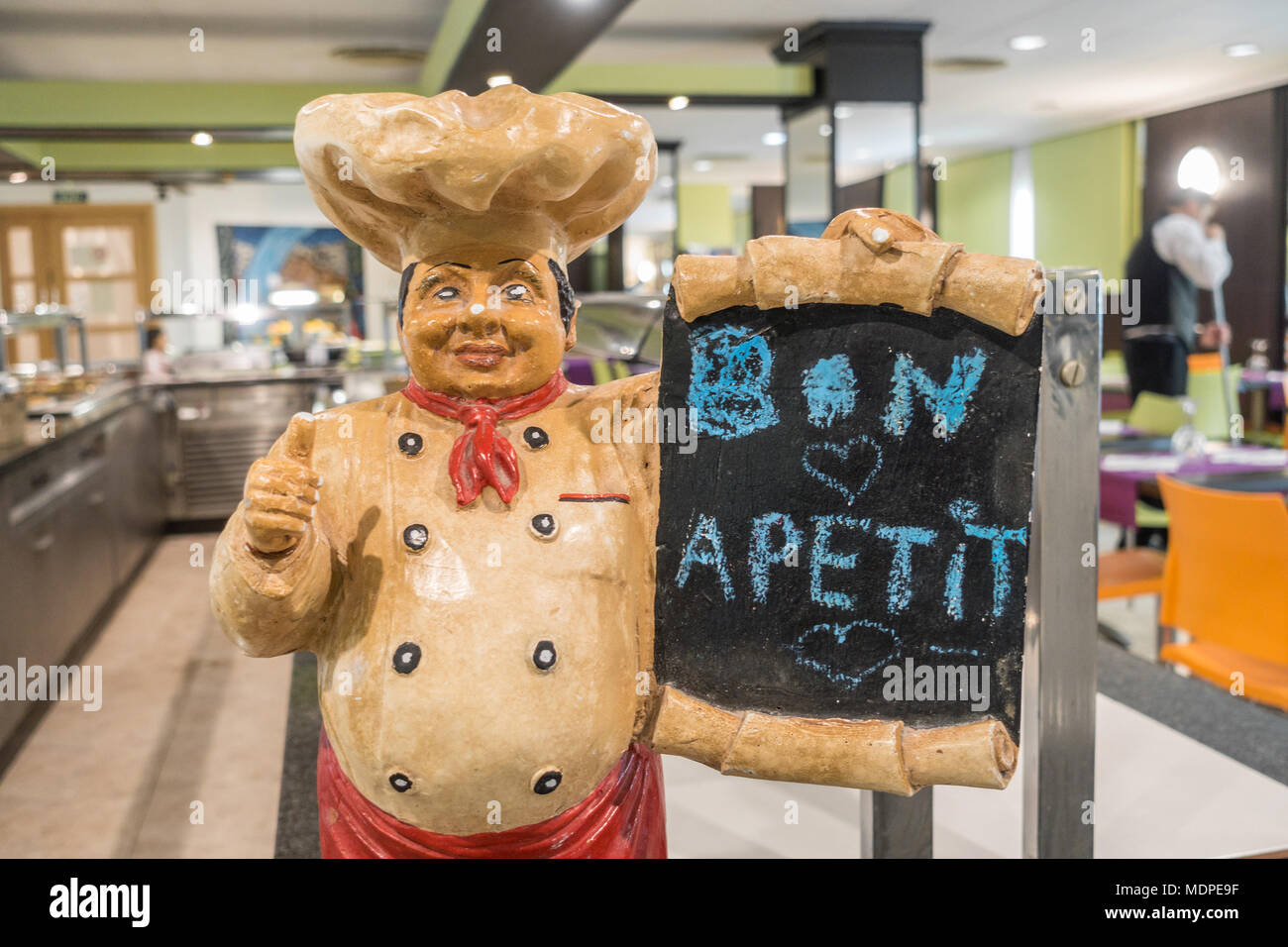 Una figura di uno chef fatta di ceramica tenendo un bordo nero con il messaggio bon apetit. Foto Stock