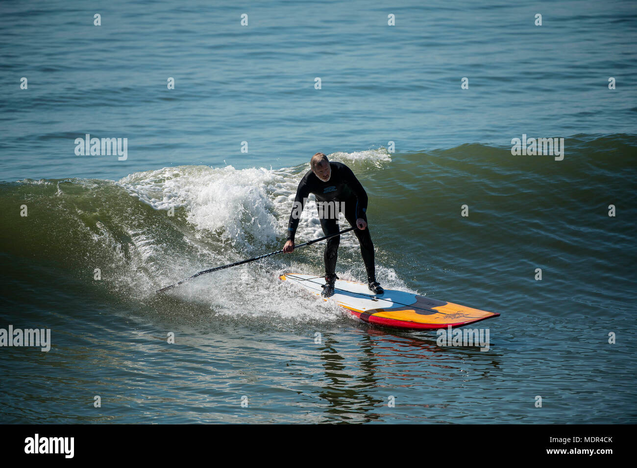 19.04.18. BOURNEMOUTH meteo. Una racchetta boarder che naviga in un'onda accanto al molo di Bournemouth come temperature salire sulla costa meridionale del Regno Unito. Foto Stock