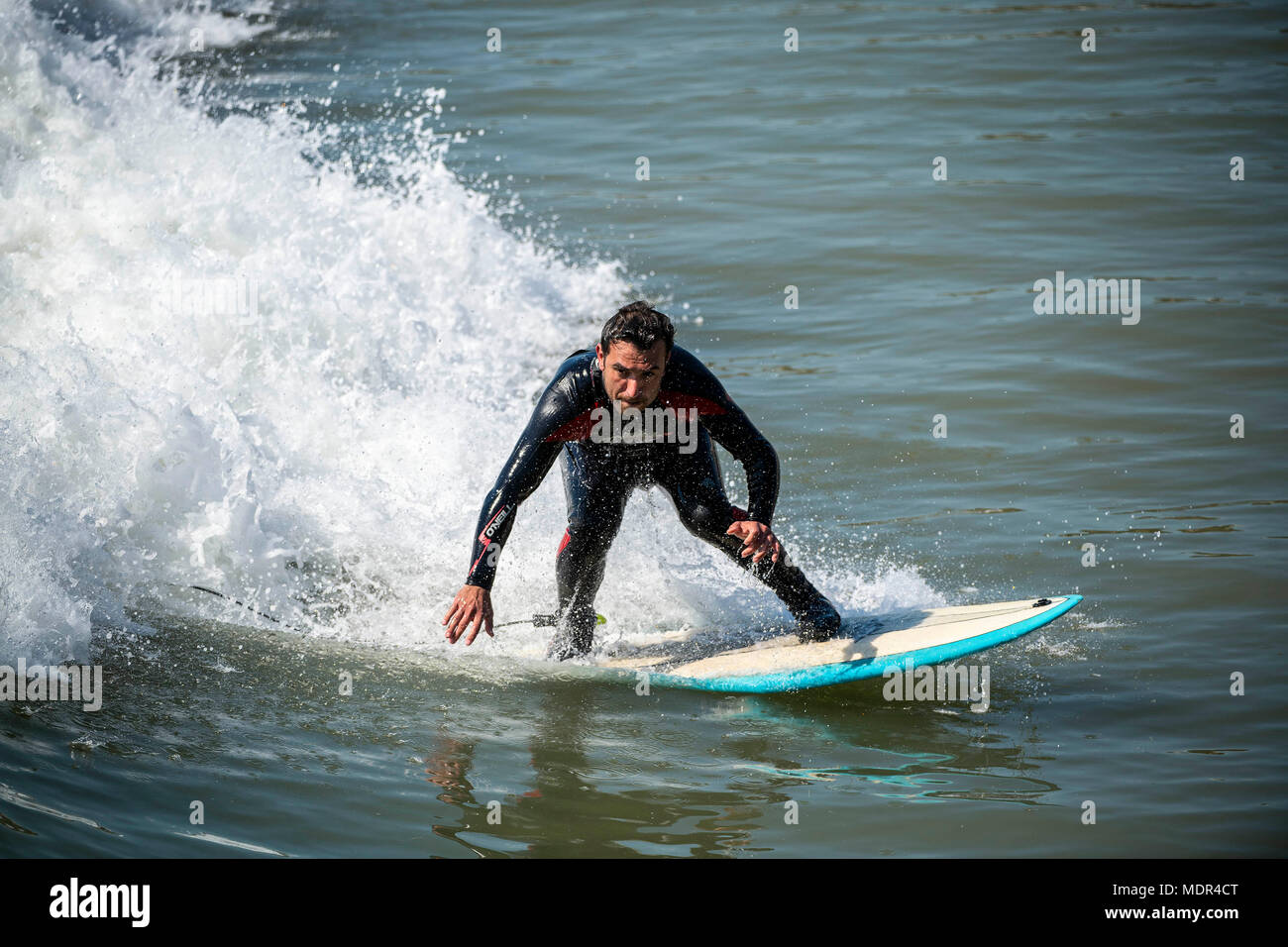 19.04.18. BOURNEMOUTH meteo. Un uomo che naviga in un'onda accanto al molo di Bournemouth come temperature salire sulla costa meridionale del Regno Unito. Foto Stock