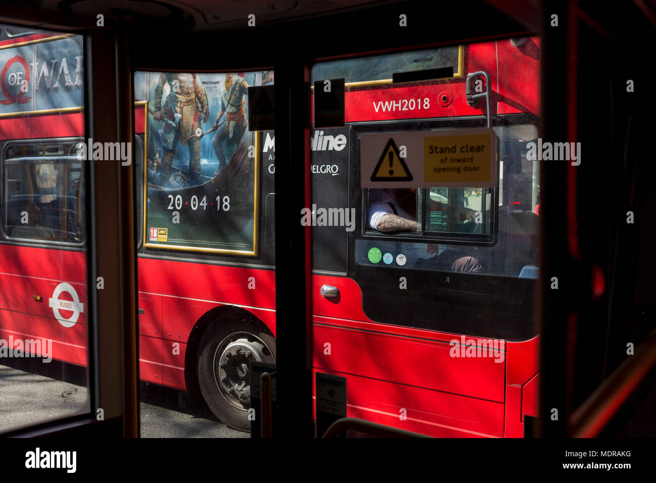 Il braccio tatuato di un autista di autobus e un annuncio per un nuovo gioco Playstation chiamato dio della guerra, il 19 aprile 2018, a Londra, in Inghilterra. Foto Stock