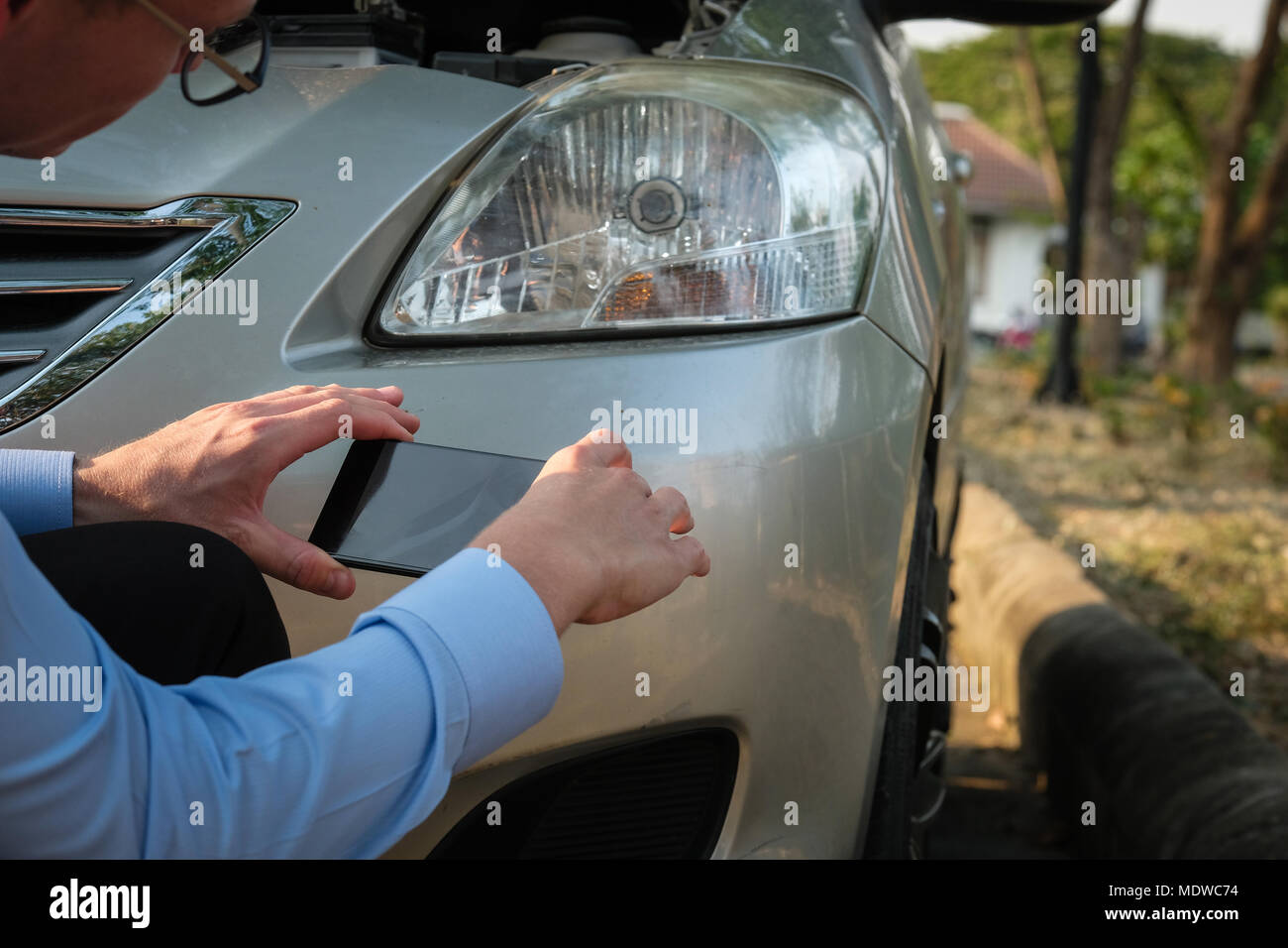 Uomo caucasico agente che tiene smart phone per scattare la foto della vettura ripartiti per incidente stradale per rivendicare assicurazione auto. Foto Stock